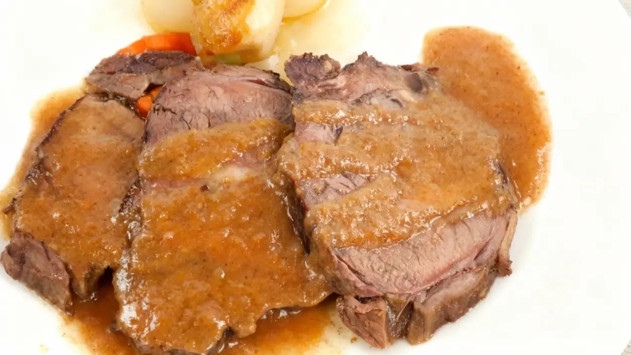 Fette di arrosto di carne con salsa servite su un piatto bianco