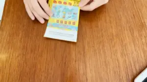Una persona tiene in mano un biglietto gratta e vinci su un tavolo in legno