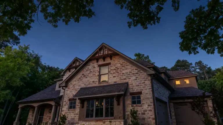 Casa in pietra immersa nel verde al tramonto, con luci accese all'interno