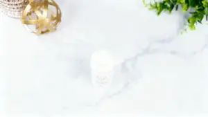 Un flacone bianco di polvere naturale su sfondo in marmo con decorazioni dorate e verdi