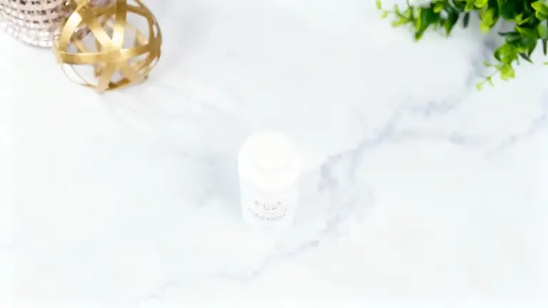 Un flacone bianco di polvere naturale su sfondo in marmo con decorazioni dorate e verdi