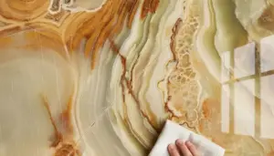 Una mano pulisce una superficie di marmo opaco con un panno bianco
