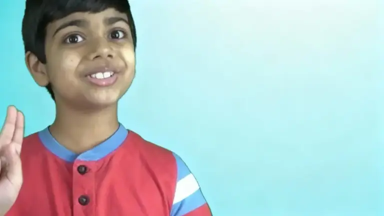 Un bambino fa un gesto con la mano su sfondo azzurro chiaro