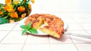 Frittata alta e soffice servita su un piatto con foglie di basilico fresco