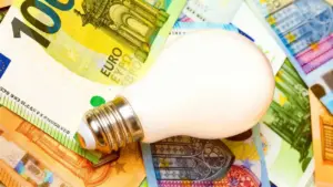 Lampadina poggiata su banconote in euro, simbolo di costi luce e gas