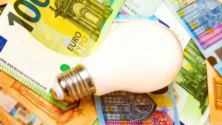 Lampadina poggiata su banconote in euro, simbolo di costi luce e gas