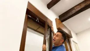 Persona cerca di aprire una finestra bloccata in legno all'interno di una stanza