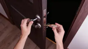 Mani che applicano olio su una serratura di porta in legno scuro